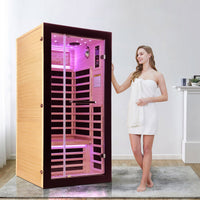 A female model standing next to a single sauna hs2 indoors A female model standing next to a single sauna hs2 indoors