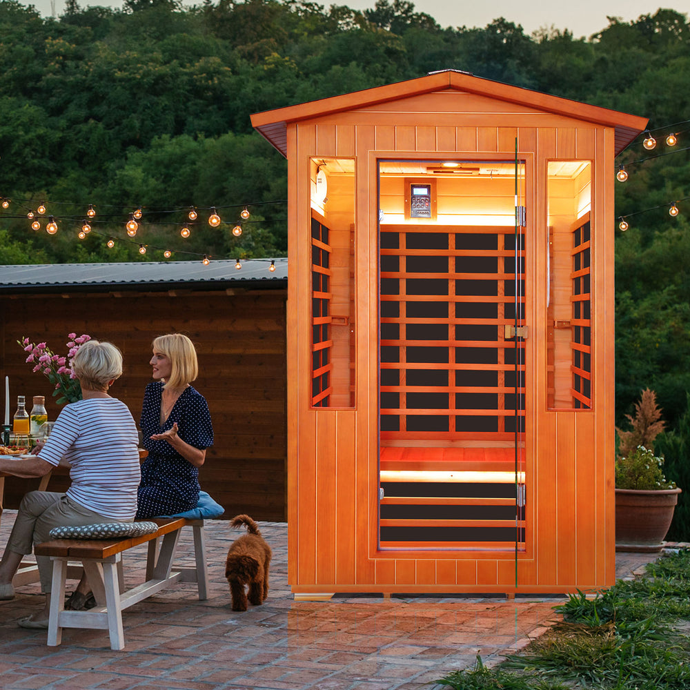 Two people sitting outside an Outexer sauna with string lights and greenery. Two people sitting outside an Outexer sauna with string lights and greenery.