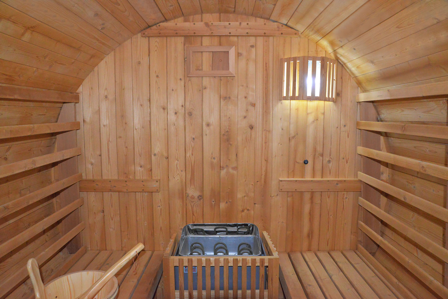 Wooden traditional sauna with benches and a hot tub.