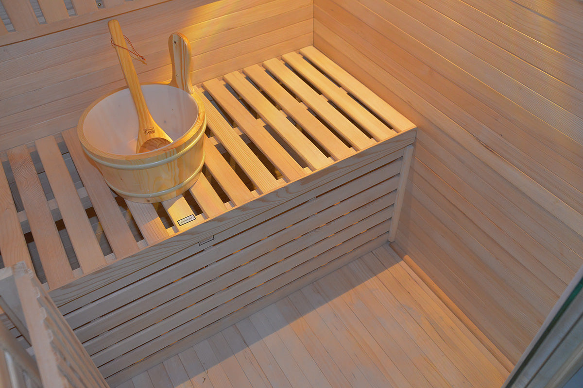 Wooden sauna bench with a bowl and ladle inside, surrounded by wooden walls.