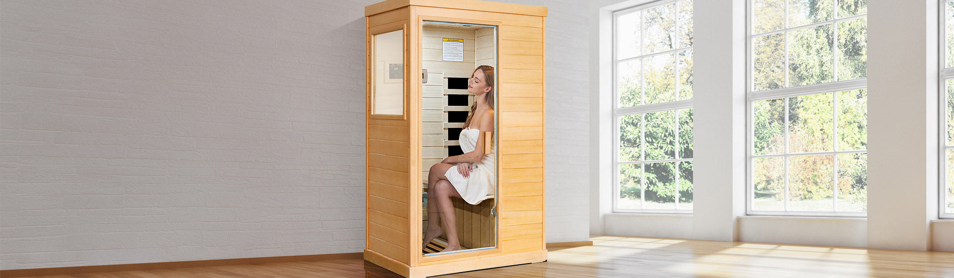 Woman sitting inside a wooden infrared sauna with large windows in the background