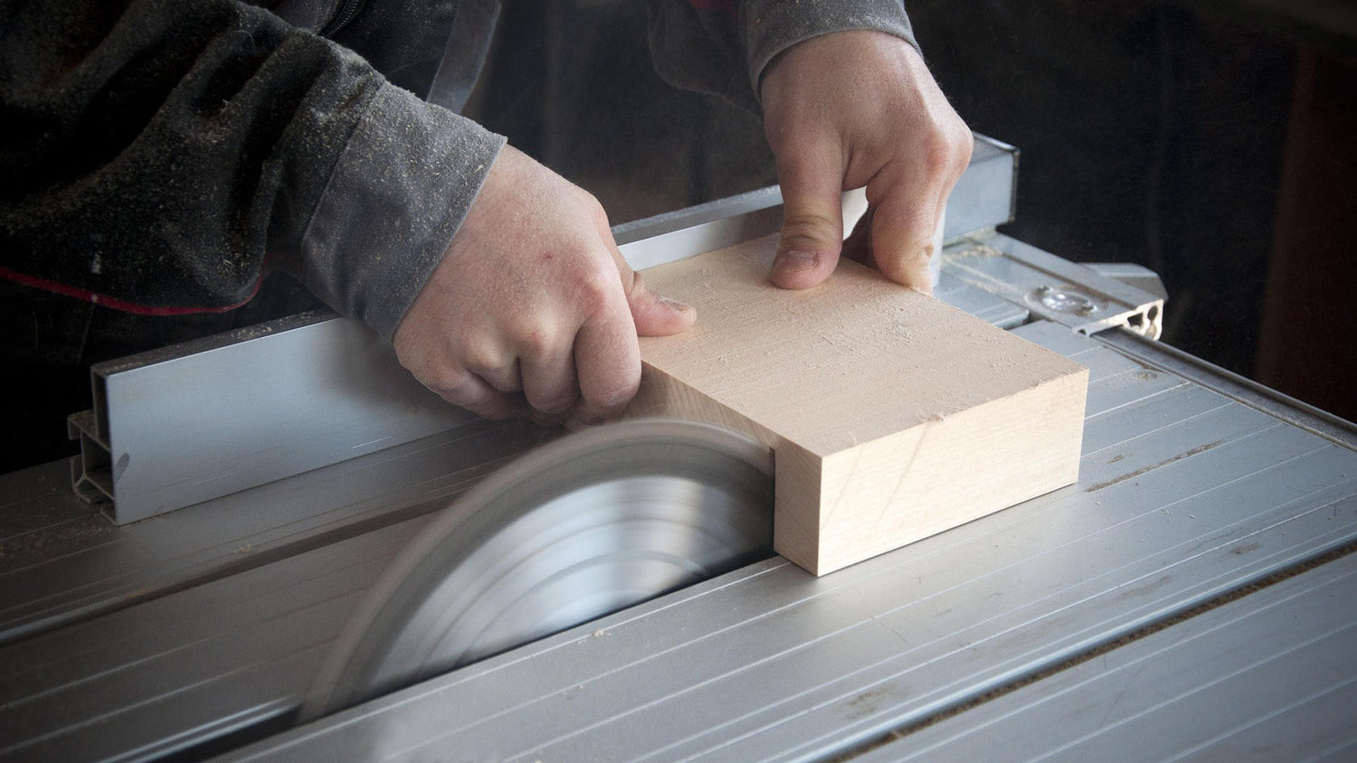 Person using a table saw to cut a piece of wood.