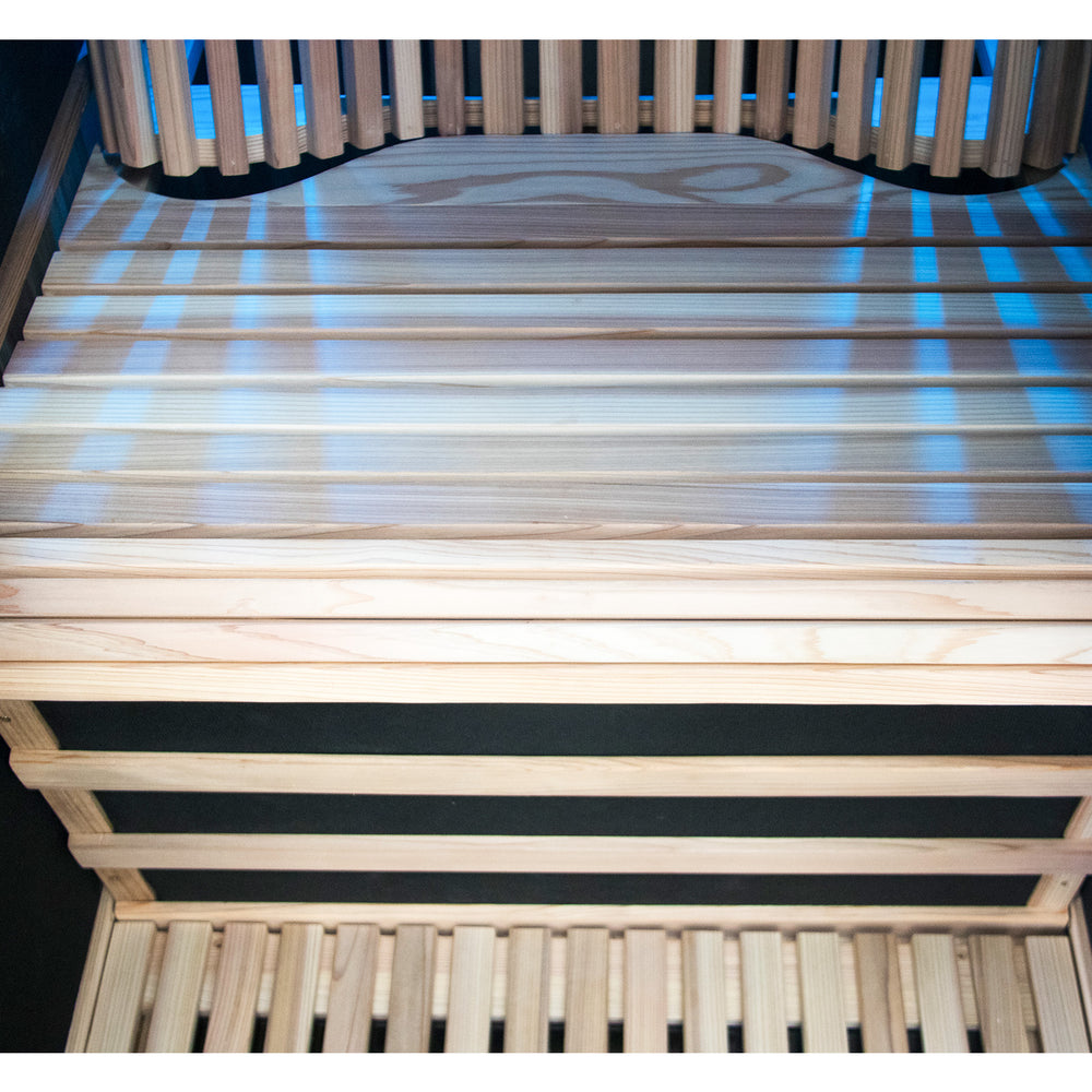 Wooden slatted seat frame with a black mattress on a dark background