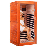 Woman sitting inside a wooden infrared sauna with striped interior.