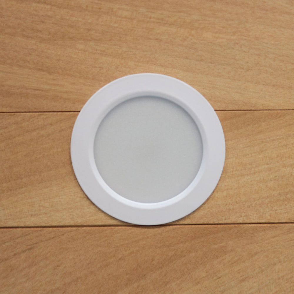 Round white LED light fixture on a wooden surface