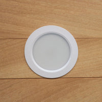 Round white LED light fixture on a wooden surface